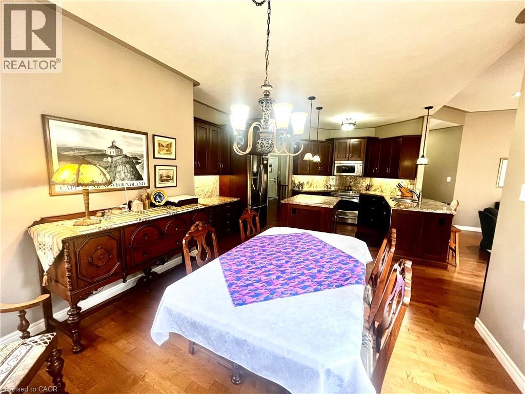 The open concept living area includes hardwood floors, a dining area with a chandelier, and a kitchen featuring dark wood cabinetry, granite countertops, and stainless steel appliances