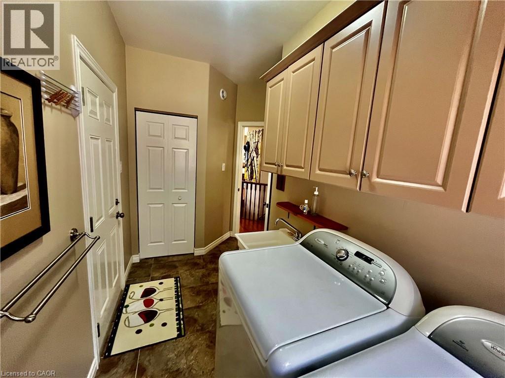 Laundry area featuring upper cabinetry with brushed nickel hardware, a utility sink, and durable tile flooring