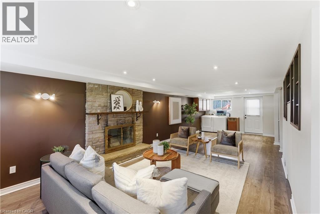 Living space featuring a stone fireplace with a wood mantle, recessed lighting, and wood-finish flooring