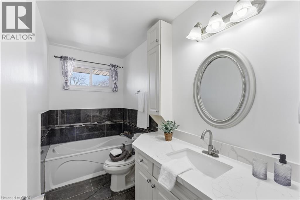 Bathroom featuring a single vanity with an integrated sink and brushed nickel faucet, an oval mirror, and a wall-mounted light fixture
