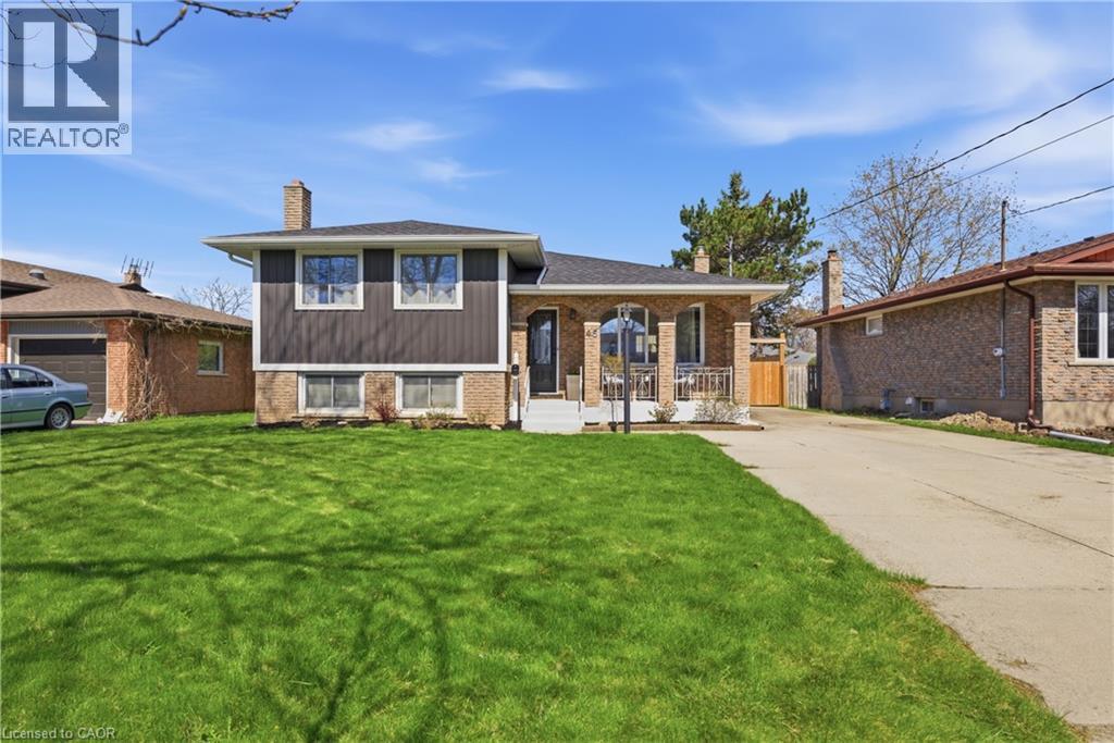 Brick and siding exterior featuring a covered front porch with white railings, a concrete driveway, and a spacious front lawn