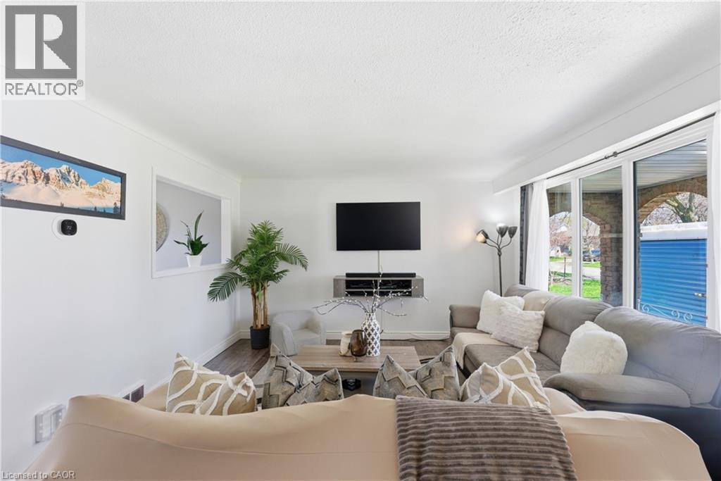 Living area featuring expansive window wall, wood-finish flooring, recessed wall opening, and a mounted media console