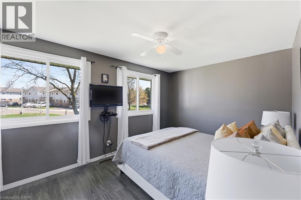 Room featuring multiple windows, a ceiling fan, and wood-finish flooring