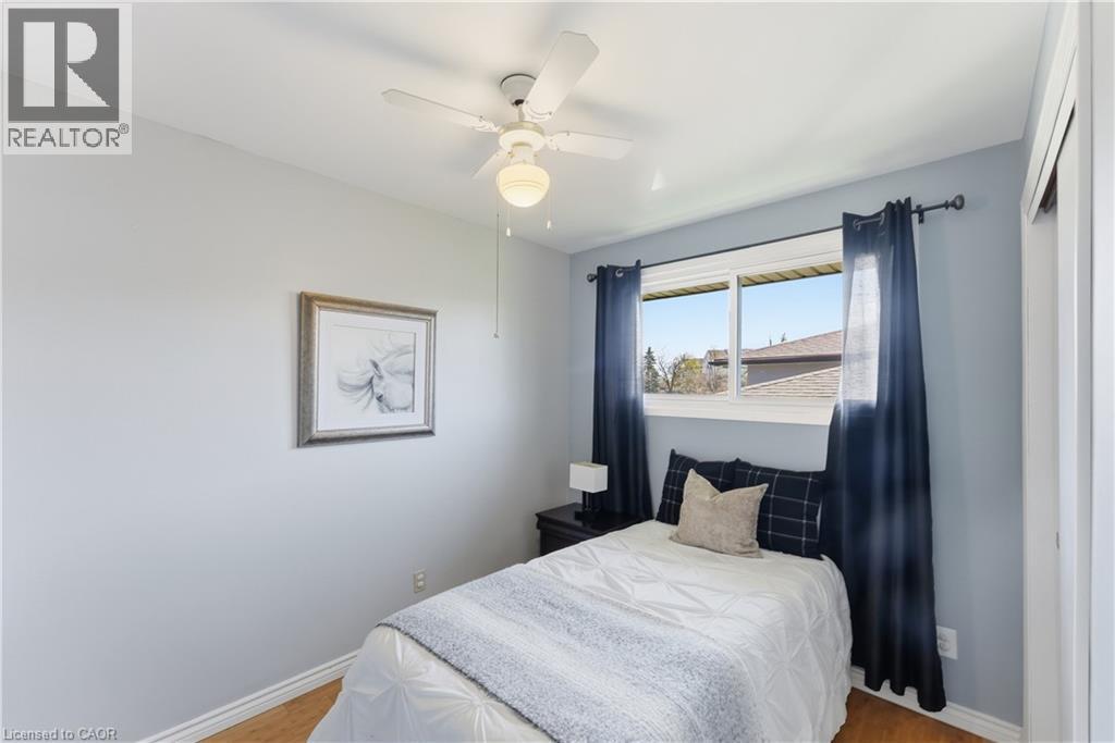 Bedroom featuring wood-finish flooring, a ceiling fan with integrated lighting, and a large window with white trim
