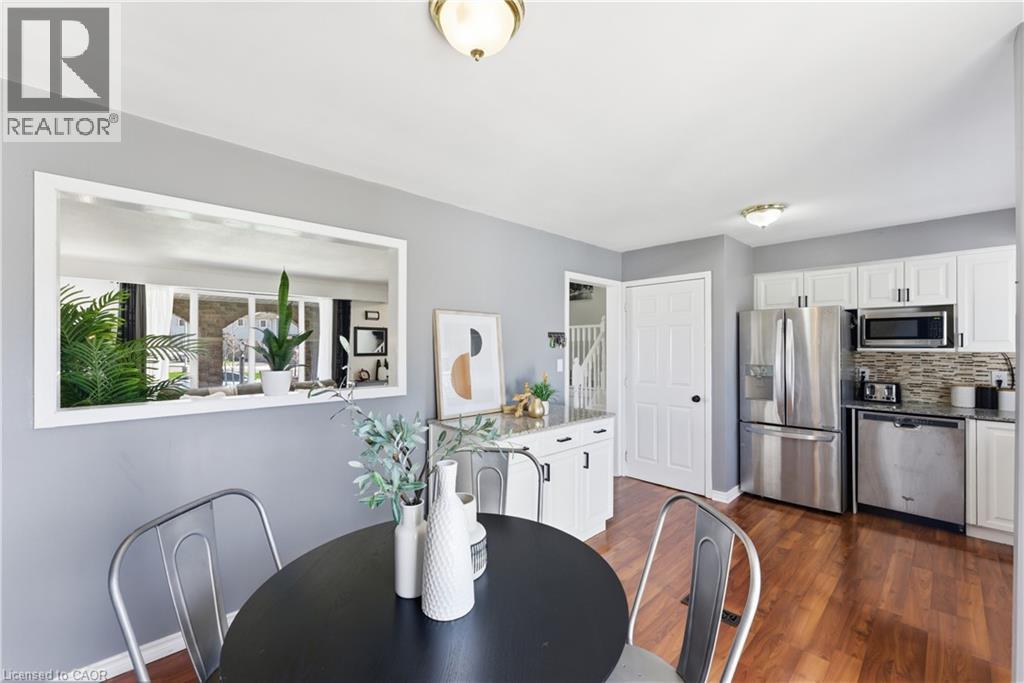 Kitchen with wood-finish flooring, white cabinetry, and stainless steel appliances
