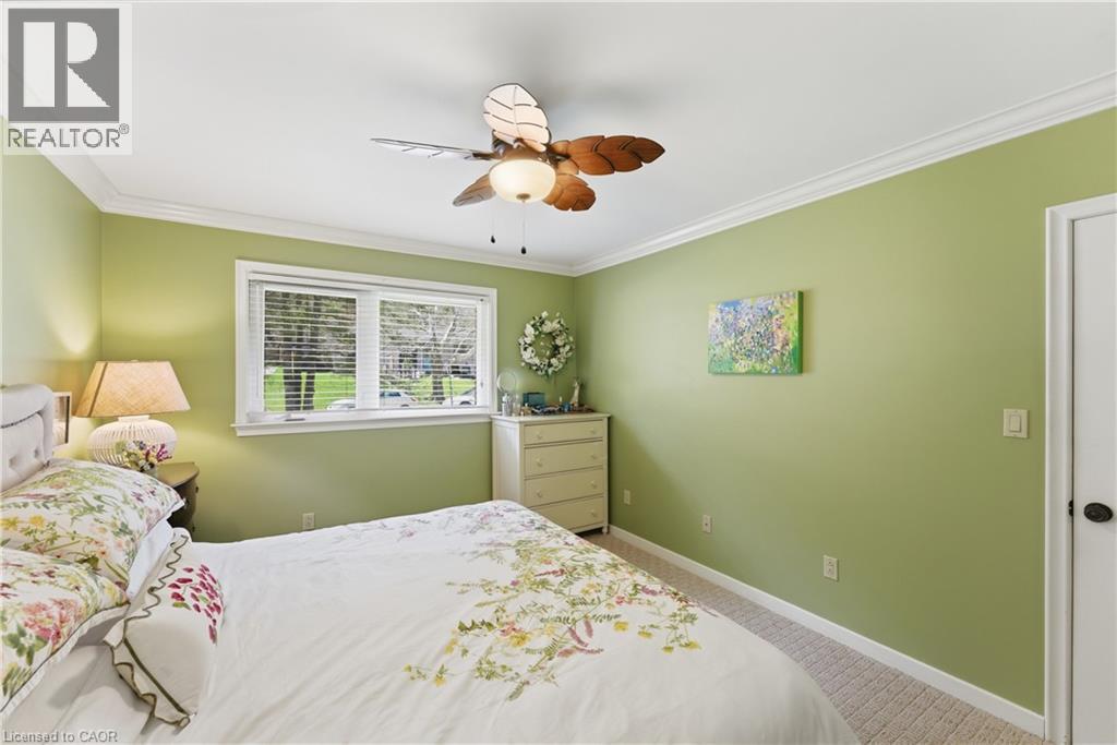 Bedroom featuring a single window with blinds, crown molding, a ceiling fan with light fixture, and carpeted flooring