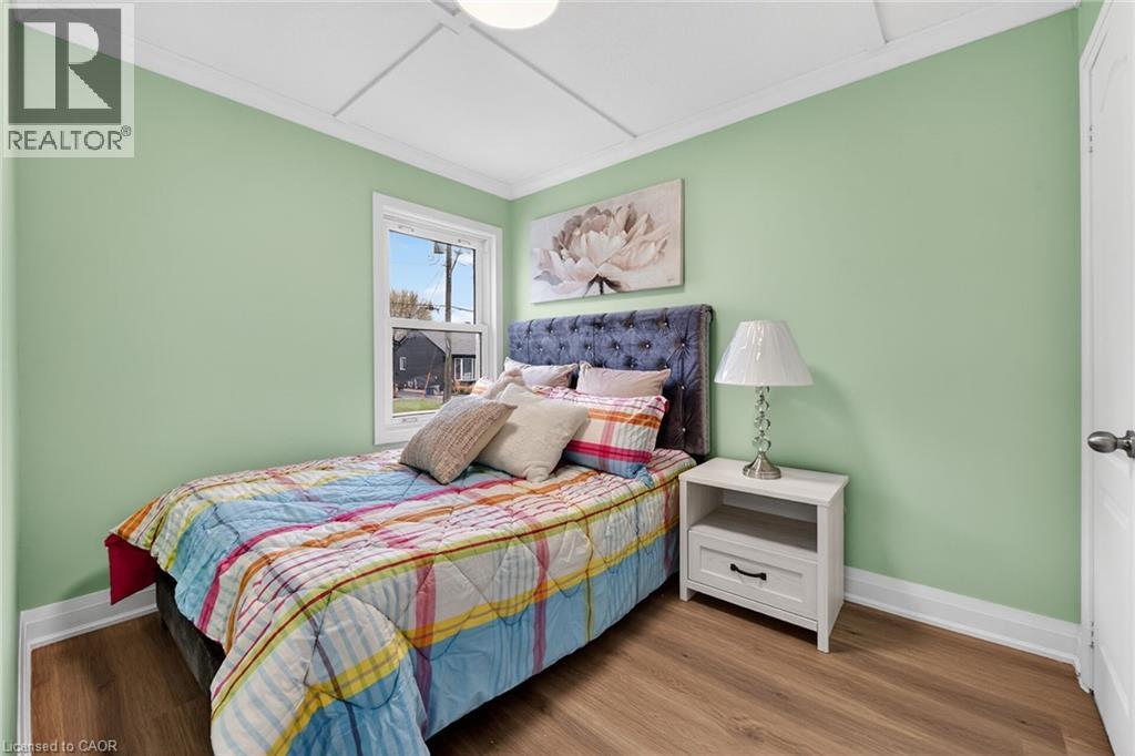 Room featuring wood-finish flooring, light green walls, white trim, and a single window with white framing
