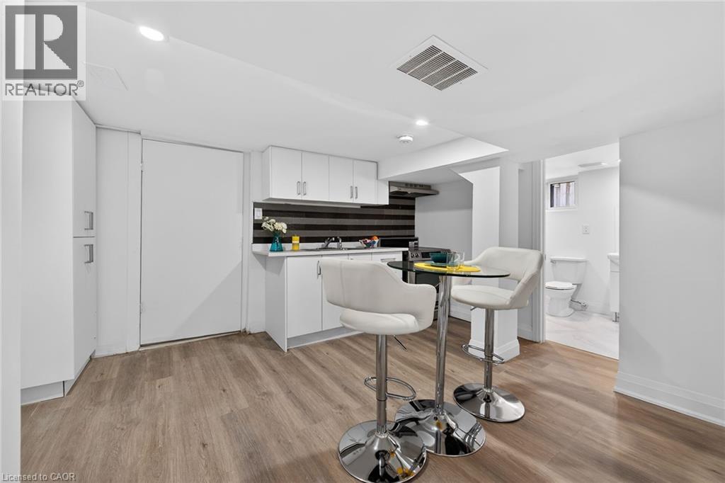 Modern kitchenette featuring white cabinetry, a dark striped backsplash, and stainless steel fixtures