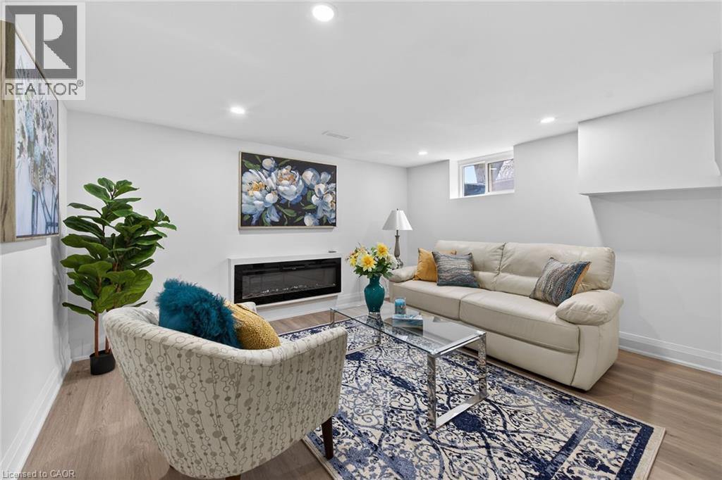 Living area featuring wood-finish flooring, recessed lighting, a modern electric fireplace, and a window providing natural light
