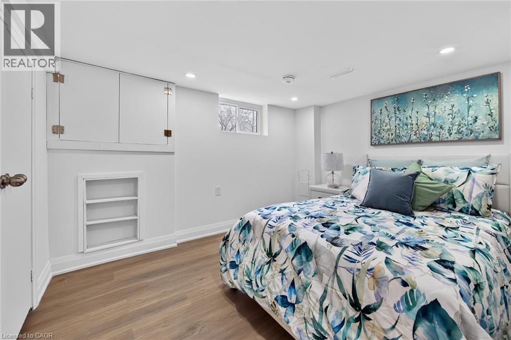 Bedroom featuring wood-finish flooring, recessed lighting, a built-in shelving niche, white baseboards, and a window
