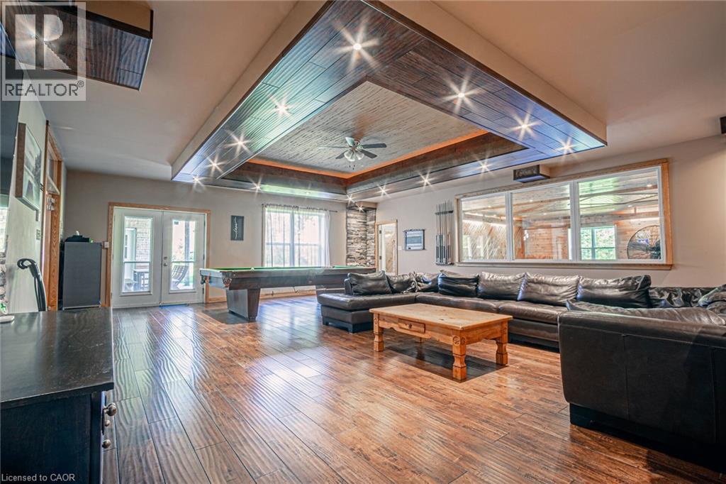 Spacious room featuring wood-finish flooring, a tray ceiling with recessed lighting, and a ceiling fan