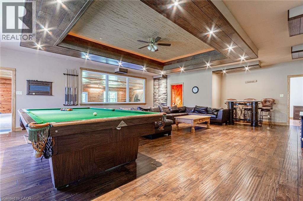 Recreation room featuring wood-finish flooring, a built-in wet bar, and a recessed ceiling design with integrated lighting