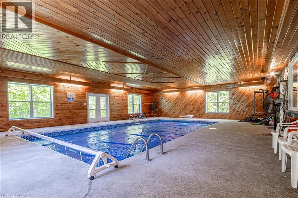 Indoor swimming pool featuring a concrete deck and natural wood-paneled walls and ceiling