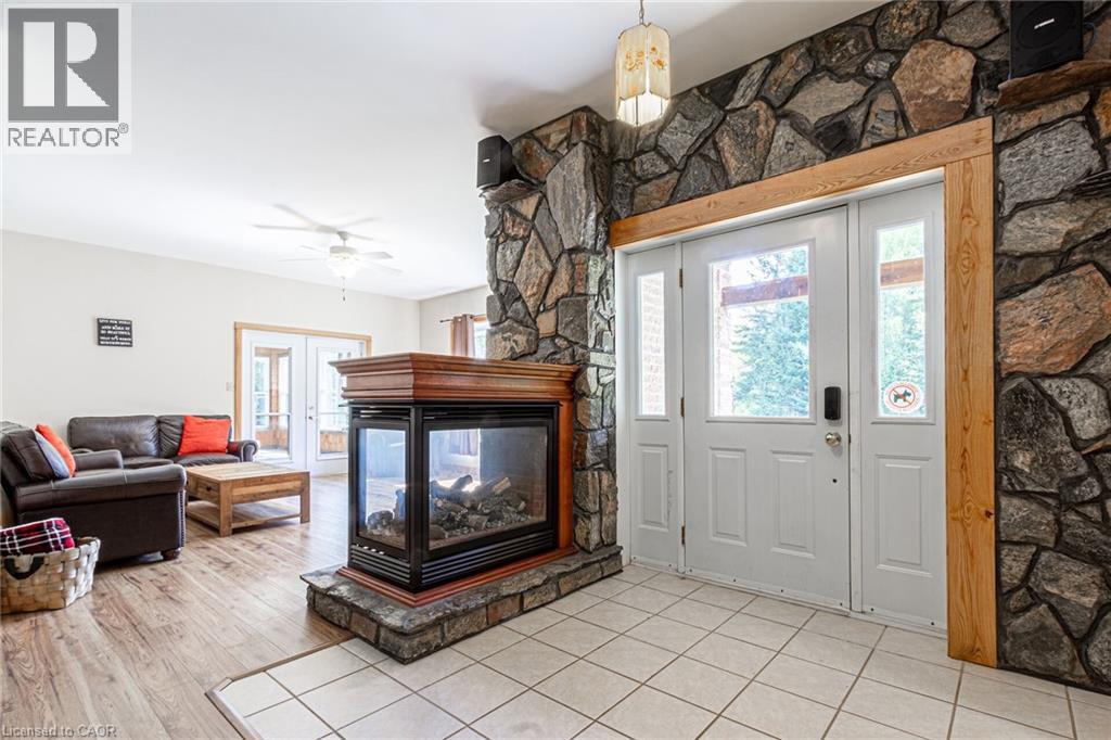 Stone-clad fireplace with wood-finish mantel and a three-sided glass enclosure