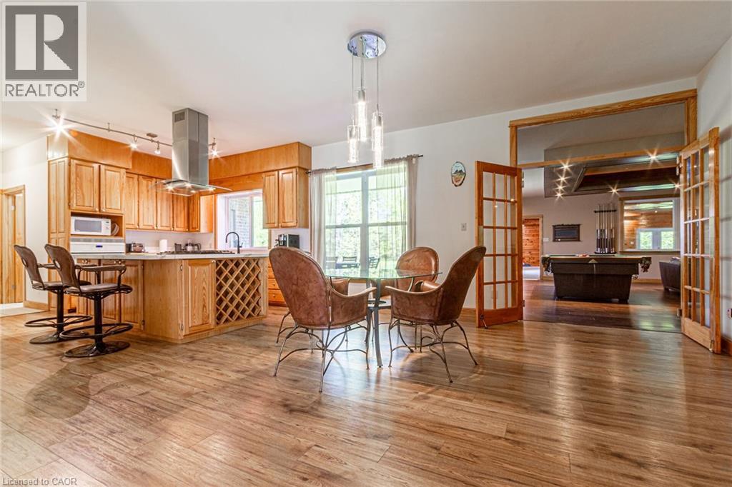 Open-concept kitchen and dining area featuring wood-finish flooring, light wood cabinetry, and an island with built-in wine storage
