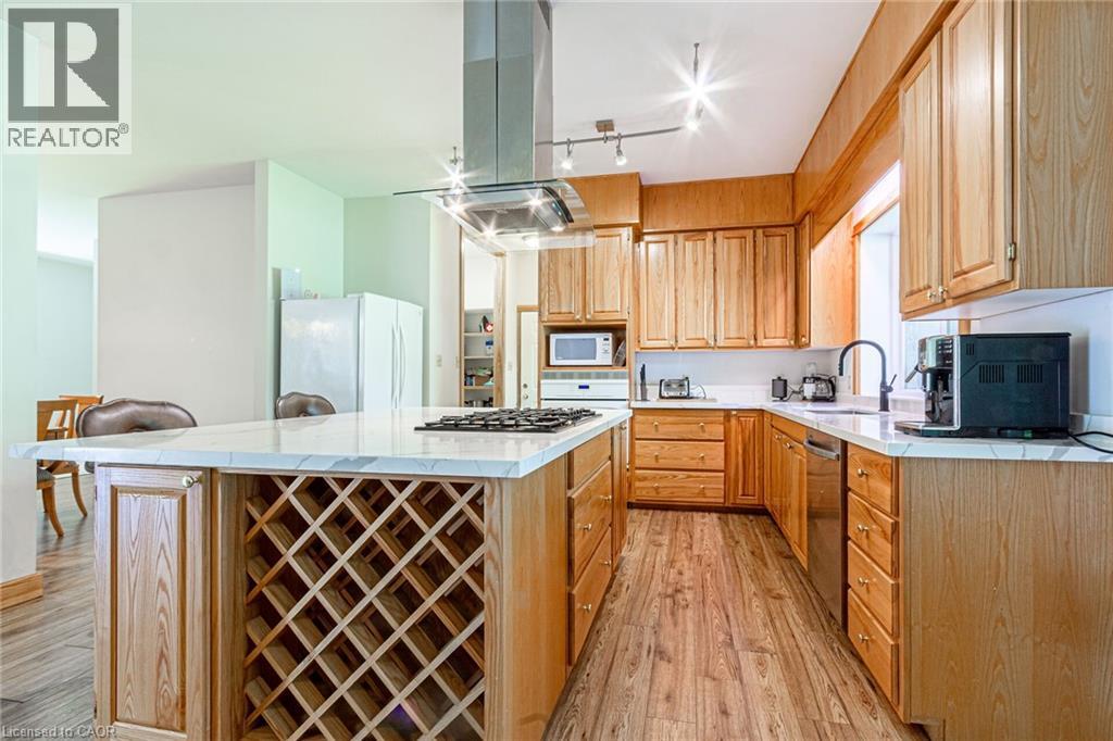 Kitchen featuring a central island with integrated wine rack, extensive light wood cabinetry, white countertops, and wood-finish flooring