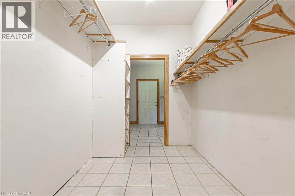 Spacious walk-in closet featuring white tile flooring and built-in shelving with hanging rods