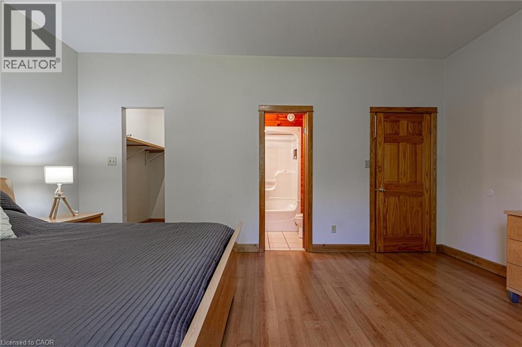 Spacious interior featuring wood-finish flooring, a walk-in closet with built-in shelving, a full bathroom with a tub and shower combination, and a paneled wood door