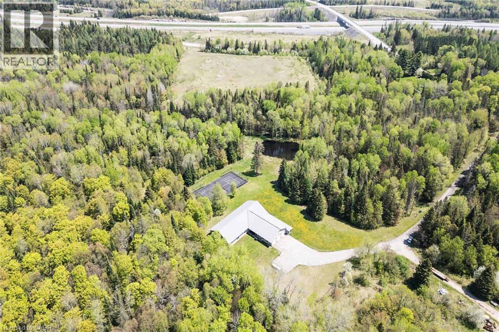 Expansive acreage featuring a private pond, a tennis court, a gravel driveway, and surrounding mature woodland