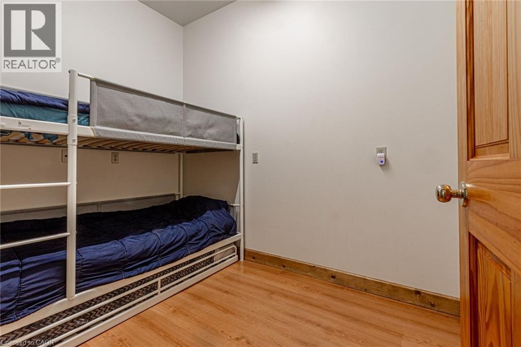 Room featuring wood-finish flooring, white walls, and a natural wood door with a brass-tone knob