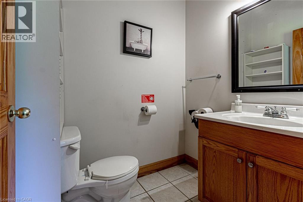Bathroom featuring a vanity with a wood-finish cabinet, white countertop with integrated sink, and a framed wall mirror