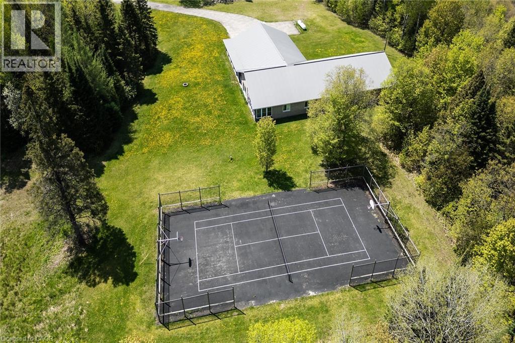Outdoor sports court with perimeter fencing, surrounded by mature trees and manicured lawn