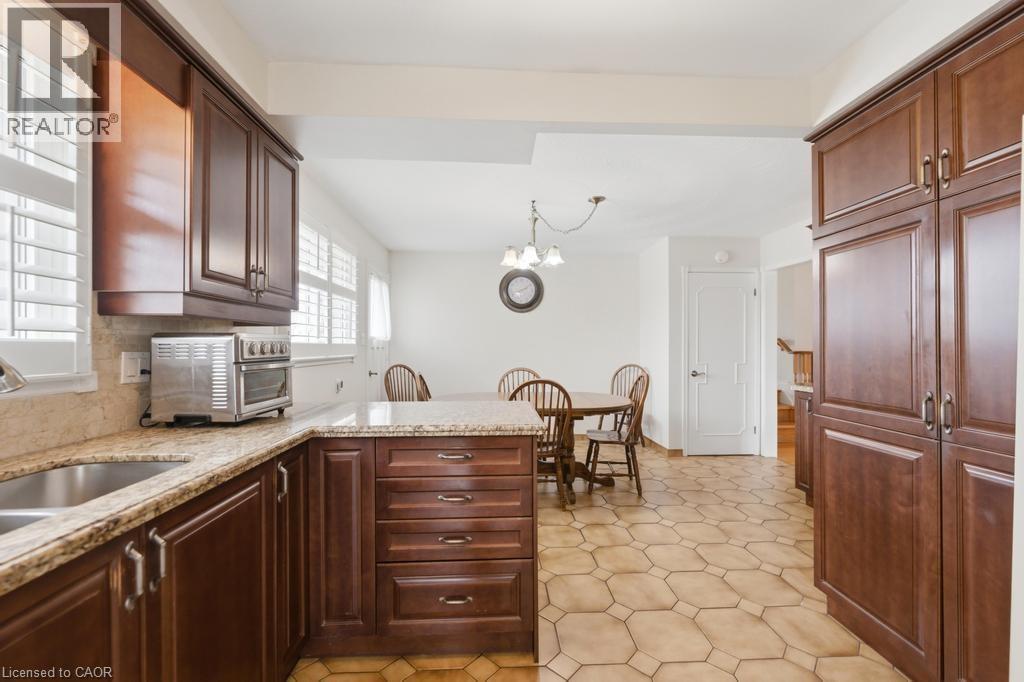 Kitchen featuring dark wood cabinetry, light-toned stone countertops, and a double basin stainless steel sink
