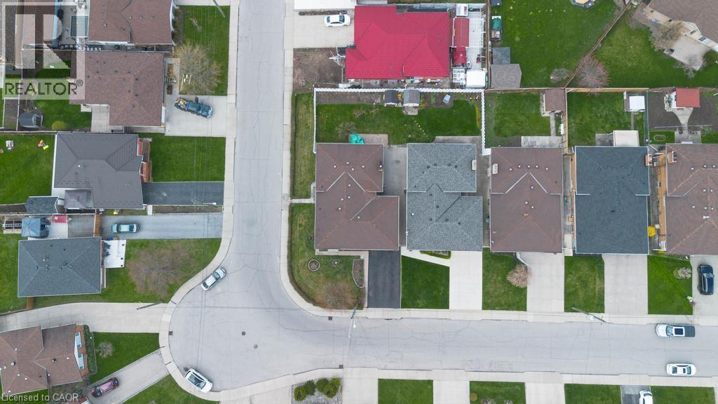 Aerial perspective of a residential street featuring multiple properties with varied roof colors, private driveways, and manicured lawns