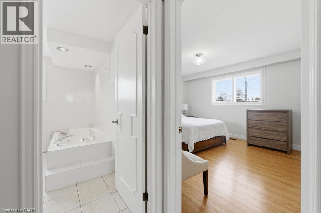 White porcelain tile flooring in the bathroom featuring a built-in jetted tub with chrome fixtures and recessed lighting