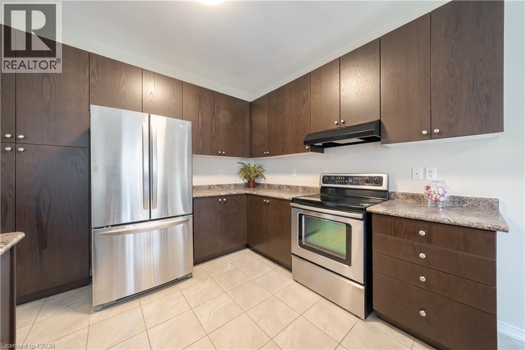Kitchen featuring dark wood-finish cabinetry, stainless steel appliances, speckled countertops, and light-toned floor tiling