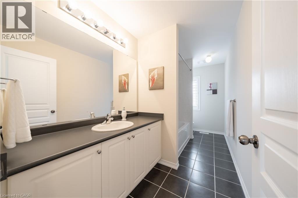 Bathroom vanity with a single basin sink, dark countertop, and white cabinetry