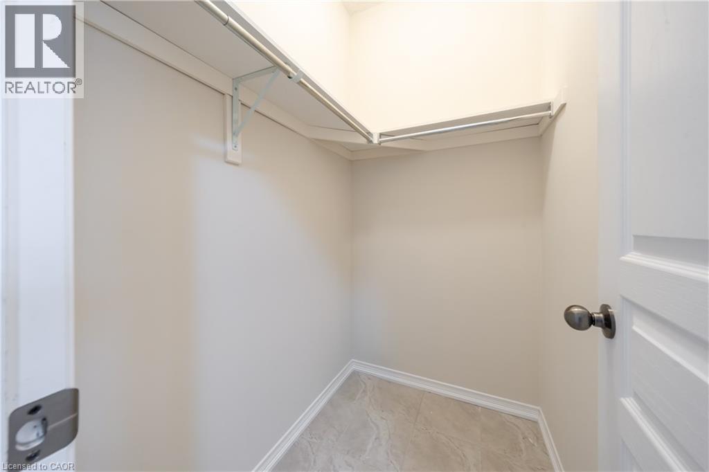 White-painted closet featuring a built-in shelf and hanging rod, light neutral wall paint, and tile flooring