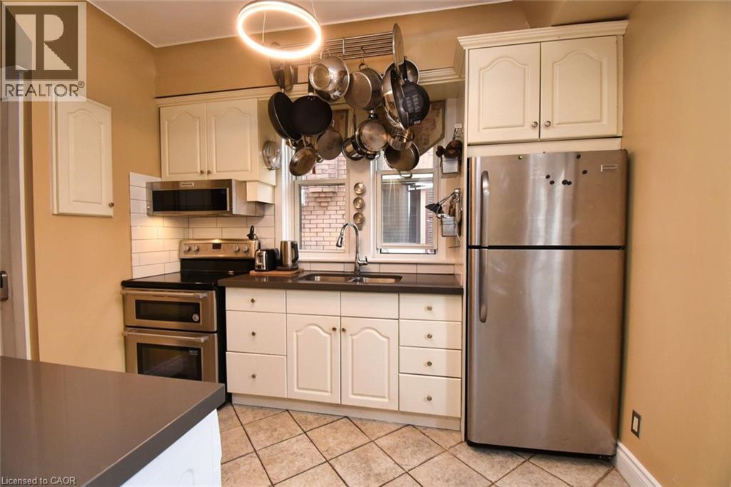 Kitchen featuring ceramic tile flooring, white cabinetry, dark countertops, a stainless steel double oven range, and an over-the-range microwave