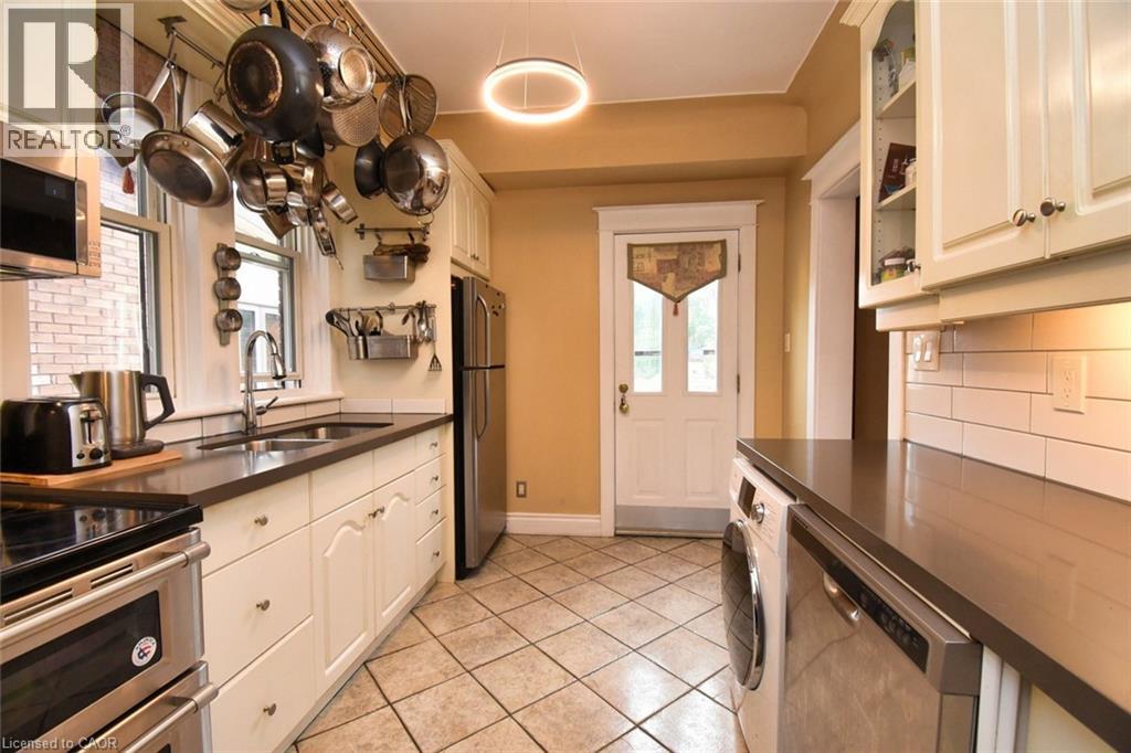Kitchen featuring white cabinetry, dark countertops, a stainless steel refrigerator, and a built-in dishwasher