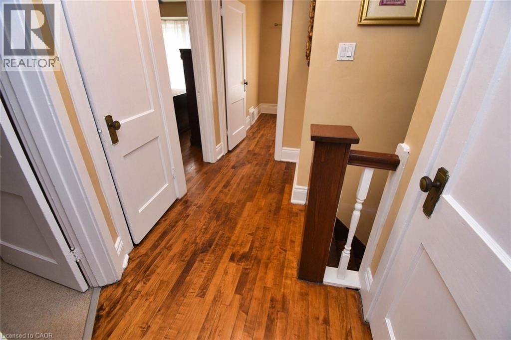 Hallway featuring wood-finish flooring, light tan walls, and white trim