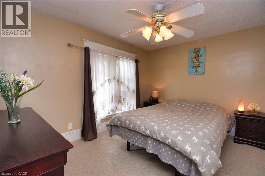 Bedroom featuring a ceiling fan with integrated lighting, window with decorative curtains, and light-toned wall paint