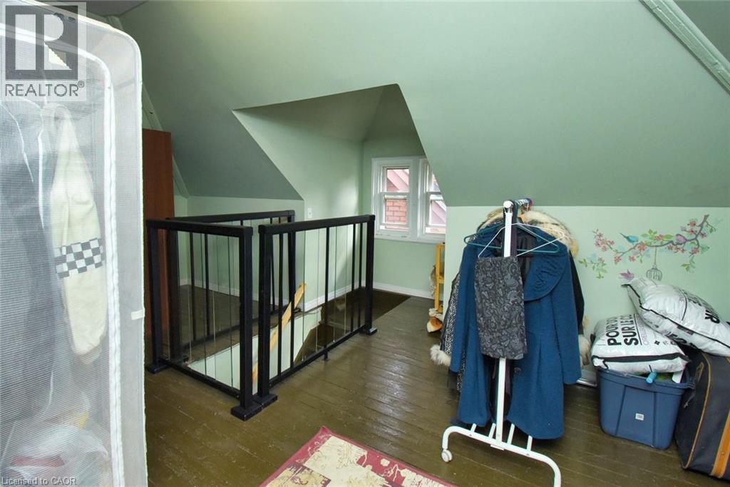 Upper-level room featuring an open staircase with black metal railings, a white framed window, and pitched ceilings