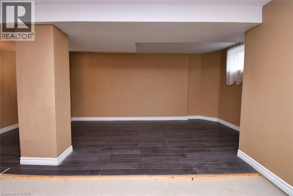 Spacious room featuring dark wood-finish flooring, light tan walls, and white trim