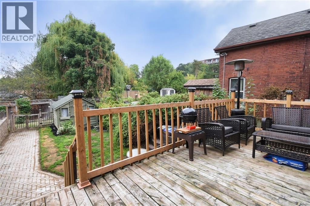 Spacious wood-finish deck with natural wood railings, overlooking a paved walkway and a detached shed