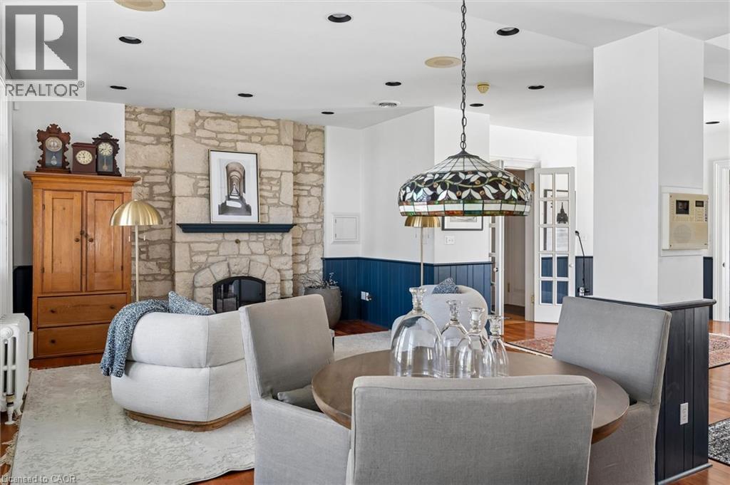 Stone fireplace with a black mantle, recessed lighting, wood-finish flooring, half-wall paneling, and a stained glass pendant light fixture