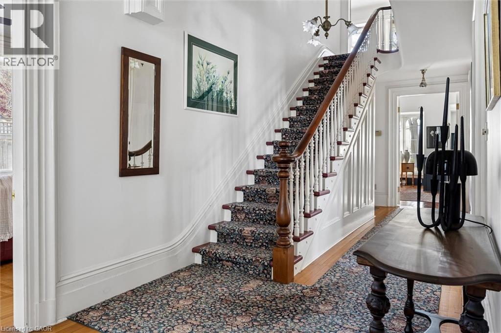 Grand staircase featuring a dark wood handrail, white balusters, and a patterned runner