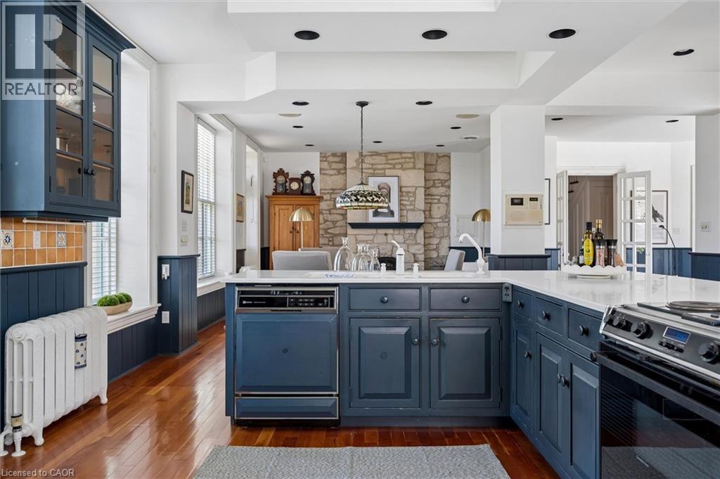 Kitchen featuring custom blue cabinetry, white countertops, built-in dishwasher, and wood-finish flooring
