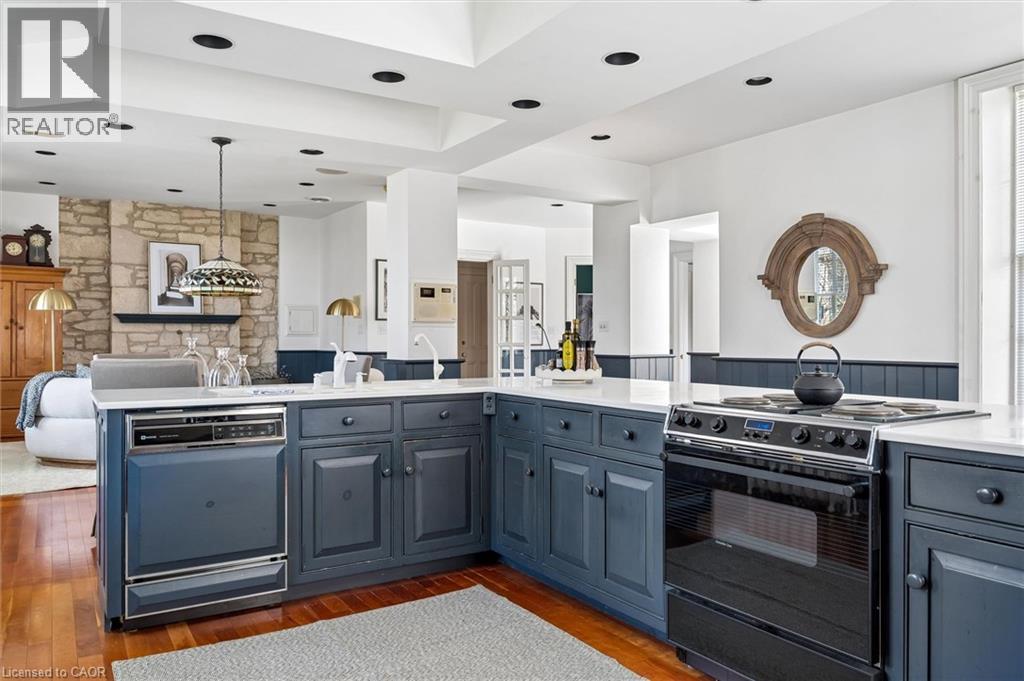 Kitchen featuring blue cabinetry, white countertops, built-in dishwasher, and a black range
