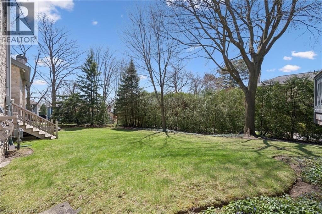 Expansive green lawn with mature trees and established perimeter shrubbery