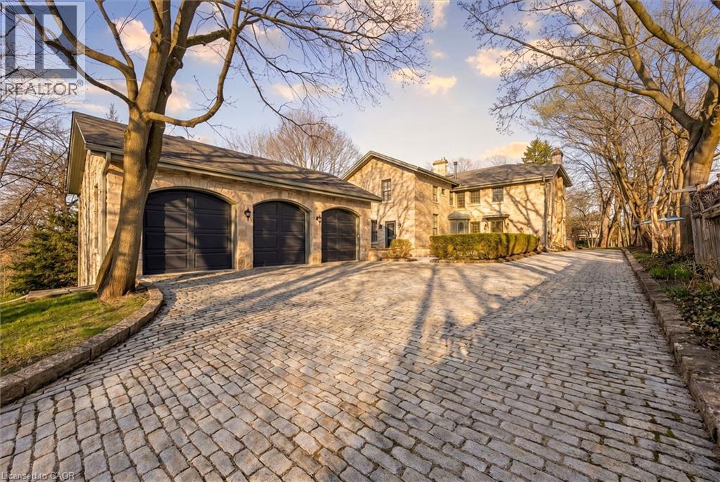 Stone-clad exterior featuring a three-car garage with arched doors