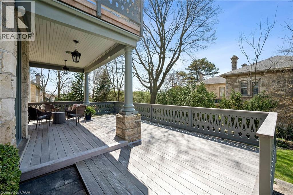 Spacious outdoor deck featuring wood-finish flooring, a decorative balustrade, and a covered porch with column supports