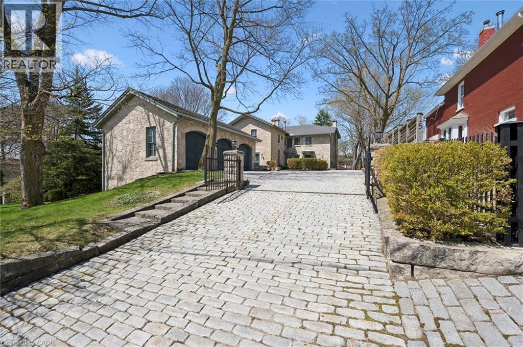 Cobblestone driveway leading to a stone-clad garage with arched doors