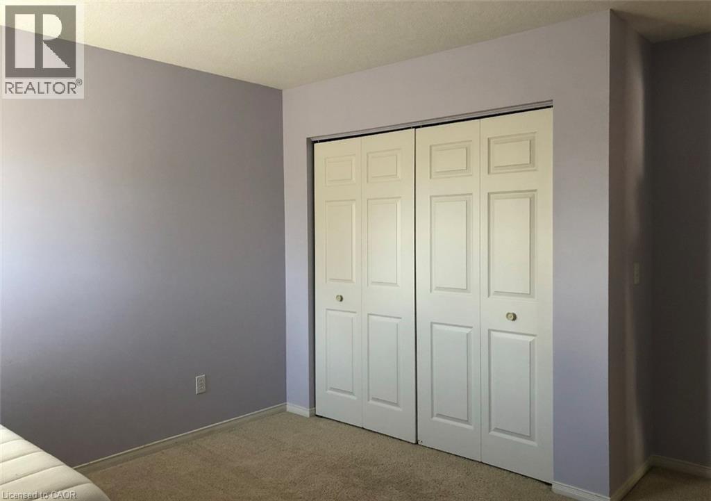 Bedroom featuring bi-fold panel doors with white trim, light purple wall paint, and neutral carpeting
