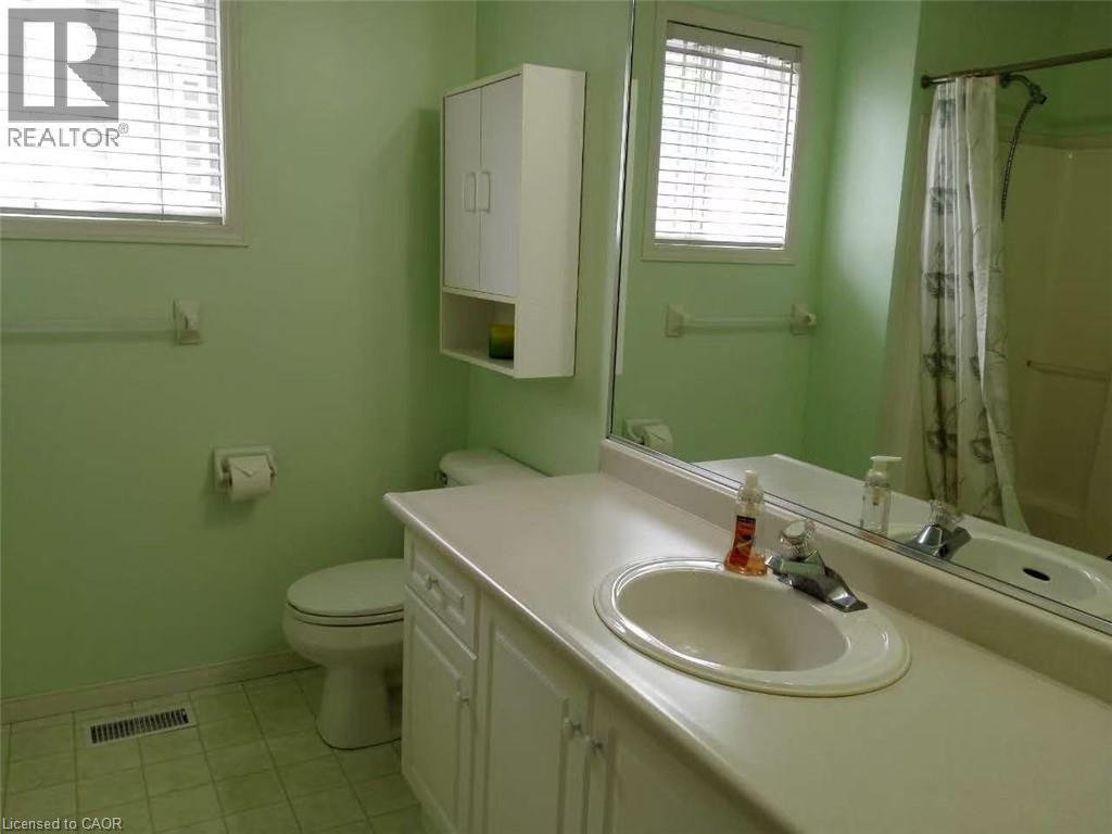 Bathroom featuring a single vanity with an integrated sink, white cabinetry, a built-in shower/tub combination, and a window with blinds