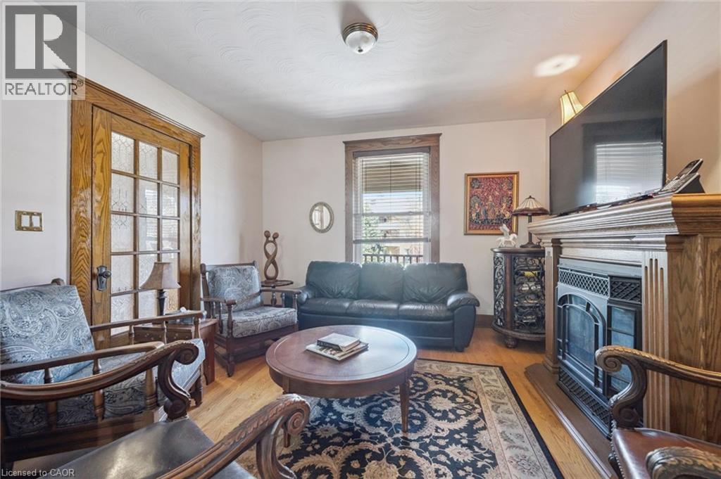 Living area featuring wood-finish flooring, a fireplace with an ornate wood mantel, and a multi-pane glass door with wood trim